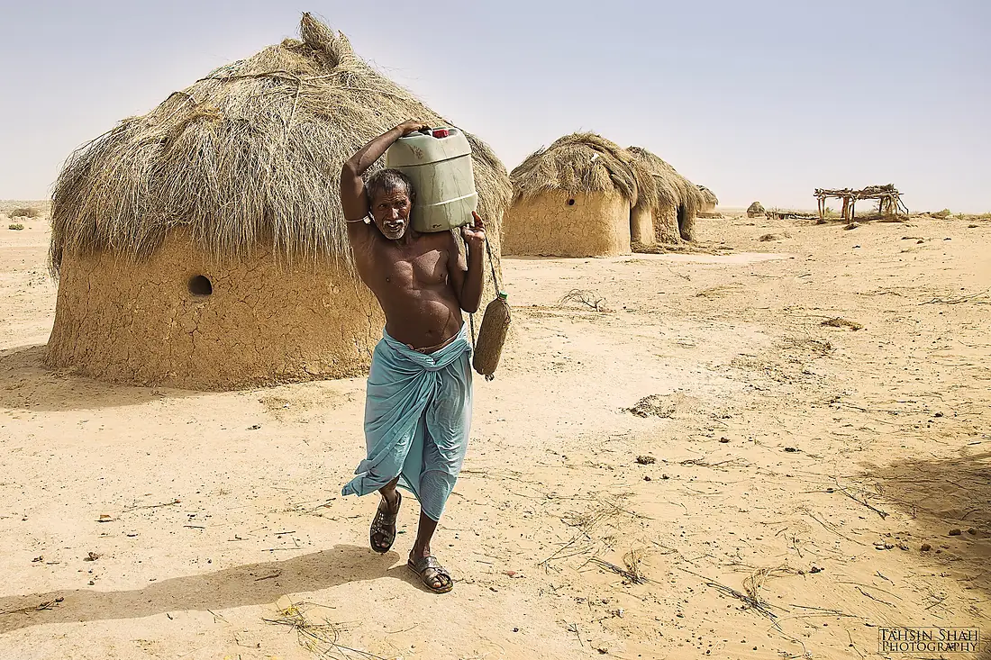 A semi-nomadic man carries water in the Cholistan Desert