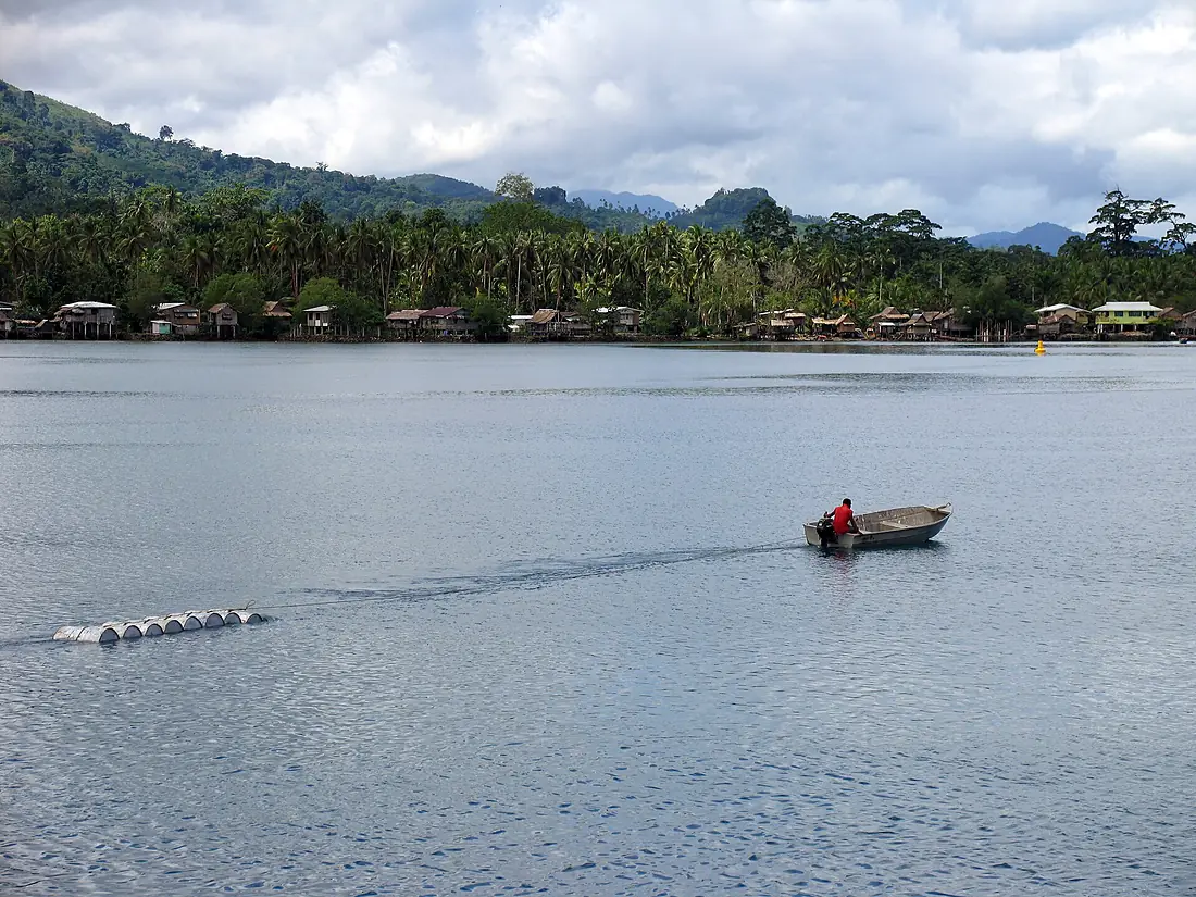 A man drags barrels of fuel behind his OBM in Auki, Malaita. (10662235174)